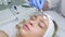 Beautician applying facial peeling mask with brush. Woman skin procedure. Cosmetologist applies oil to the client`s face in the be