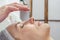 Beautician hand applies cream on face of woman in a spa salon