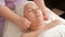 Beautician holds hands massage the face of an Asian woman. Muslim girl with closed eyes with a towel on her head in the