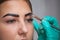 Beautician- makeup artist applies paint henna on previously plucked, design, trimmed eyebrows in a beauty salon in the session cor