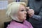 Beautician making up a blonde older woman