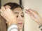 Beautician measuring the eyebrows with the special ruler for microblading on a young woman in a beauty salon