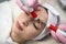 beautician performing microcurrent stimulation young woman on face at spa clinic