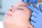 Beautician plucks out hair on eyebrows with tweezers for woman, face closeup.