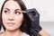 Beautician plucks a young woman`s eyebrows with tweezers