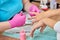 Beautician protective gloves in process of cutting cuticle to female customer.