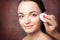 Beautician removes makeup from the face of a young beautiful woman, closeup portrait on a red background