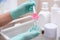 Beautician`s hands in medical gloves holding a spatula with therapy serum on a glass table with jars of creams in the beauty