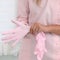 Beautician woman putting on pink rubber gloves against body background. Body and health care female health concept. Shallow dof,