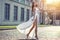 Beautifilul elegant woman in long white flattering dress walking