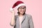 Beautifiul caucasian manager woman in red Santa hat on pink studio background.