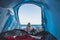 Beautifl cheerful blonde girl smiling viewed from inside a tent camped at the beach directly on the sand - travel and summer