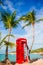 Beautiftul woman near red phone booth in Dickenson`s bay Antigua. Beautiful landscape with a classic phone booth on the