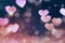 Beautiful abstract blurred pink hearts on dark background..
