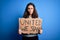 Beautiful activist woman holding banner with united stand message over blue background with a confident expression on smart face