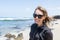 Beautiful adult female poses at La Jolla Beach in San Diego, wearing sunglasses