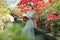 Beautiful adult girl in an azalea greenhouse reading a book and dreaming in a beautiful retro dress