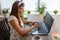 Beautiful adult woman at home in the kitchen working on a laptop