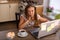 Beautiful adult woman at home in the kitchen working on a laptop