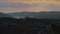 beautiful aerial panoramic view of foothills and mountains with a lake in morning twilight. Pink yellow violet sky above