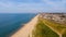 A beautiful aerial  seaside view with sandy beach, crystal blue water, groynes breakwaters and green vegetation dunes along a