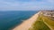 A beautiful aerial  seaside view with sandy beach, crystal blue water, groynes breakwaters and green vegetation dunes along a