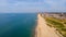 A beautiful aerial  seaside view with sandy beach, crystal blue water, groynes breakwaters and green vegetation dunes along a