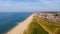 A beautiful aerial  seaside view with sandy beach, crystal blue water, groynes breakwaters and green vegetation dunes along a