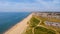 A beautiful aerial  seaside view with sandy beach, crystal blue water, groynes breakwaters, green vegetation dunes and parking