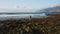 Beautiful aerial shot of female stands on rocky ocean and watching wide powerful foaming waves. Rear view of lonely