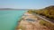 Beautiful aerial view about a coastline of a lake or sea, with reeds along the coast, turquise, blue water, mountains, and blue sk