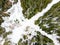 Beautiful aerial view of snow covered pine forests and a road winding among trees. Rime ice and hoar frost covering trees. Scenic