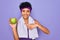 Beautiful african american afro sporty woman doing exercise wearing towel eating green apple very happy pointing with hand and