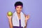 Beautiful african american afro sporty woman doing exercise wearing towel eating green apple very happy pointing with hand and