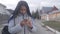 Beautiful African American girl with dreadlocks standing on the street and using smartphone. Smart teenager using social