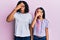 Beautiful african american mother and daughter wearing casual clothes and glasses peeking in shock covering face and eyes with