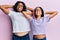 Beautiful african american mother and daughter wearing casual clothes and glasses relaxing and stretching, arms and hands behind