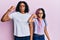 Beautiful african american mother and daughter wearing casual clothes and glasses strong person showing arm muscle, confident and