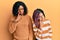 Beautiful african american mother and daughter wearing wool winter sweater pointing to the eye watching you gesture, suspicious