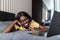 Beautiful african american professional woman laying relaxing on hotel bed, using a laptop computer, reading serene, travel