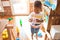 Beautiful african american toddler drinking plastic glass of water using straw at kindergarten