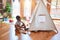 Beautiful african american toddler putting on shoes outside tipi at kindergarten