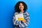 Beautiful african american woman with afro hair holding books sticking tongue out happy with funny expression