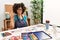 Beautiful african american woman with afro hair painting at art studio showing and pointing up with fingers number five while