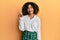 Beautiful african american woman with afro hair wearing scholar skirt showing and pointing up with finger number one while smiling