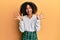 Beautiful african american woman with afro hair wearing scholar skirt showing and pointing up with fingers number ten while