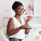 Beautiful African American Woman applying her makeup on with professional cosmetics products at home