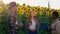 A beautiful African woman is holding the laptop while talking to two other people in a sunflower field, they are in a