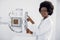 Beautiful African woman in white medical coat, standing near the X-Ray machine in modern hospital radiology room. X ray