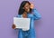 Beautiful african young woman holding blank empty banner smiling happy doing ok sign with hand on eye looking through fingers